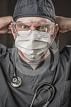 Stressed Male Doctor or Nurse Wearing Scrubs, Protective Face Mask and Goggles