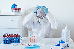 Stressed male doctor sitting tired at his desk. Mid adult male doctor working long hours in protective clothes. Covid-19