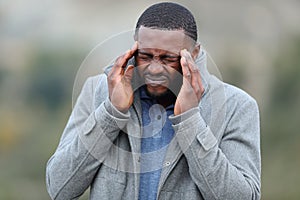 Man with black skin suffering migraine outdoors