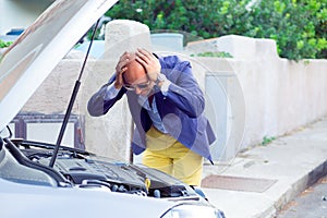 Stressed man with broken car looking at failed engine