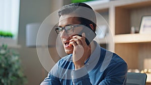 Stressed man disputing telephone call at work room close up. Businessman arguing