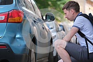 Stressed man driver sitting on street side shocked after car accident. Road safety and insurance concept