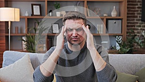 Stressed man feeling pain massaging head to relax reduce ache indoor headache.