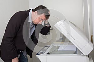 Stressed man in front of a copy machine