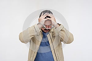 A stressed man in handcuffs under duress. Under arrest and detained for a suspected crime. Isolated on a white background photo