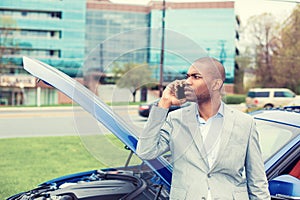 Stressed man having trouble with broken car opening hood calling for help on cell phone