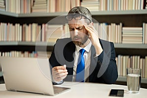Stressed man with headache. Tired businessman is working overtime and has headache. Man with laptop at workplace