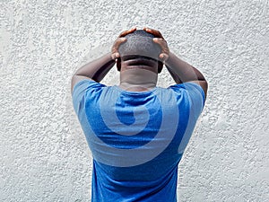 African man holding head in his hands, worried, dismayed or  unhappy expression, back view photo