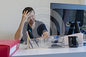 Stressed man at job into office in front of his computer.Office clerk into burn out concept