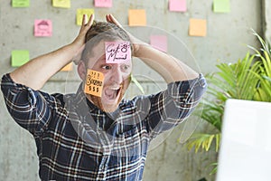 Stressed man with message on sticky notes over his face in office.