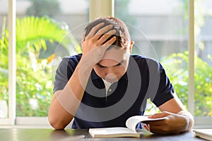 Stressed man reading book with hand on his head