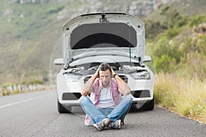 Stressed man sitting after a car breakdown