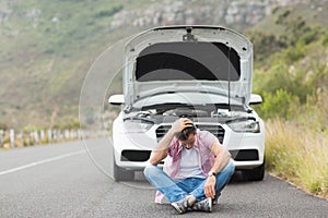 Stressed man sitting after a car breakdown at the side of the road