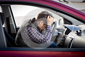 Stressed man sitting on car drivers seat