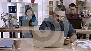 Stressed man working at desk in creative office