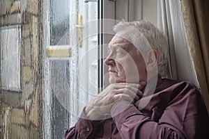 Stressed mature man looking out of window on a winters day