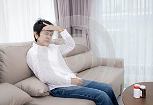 Stressed mature senior woman touching head with closed eyes at sofa in living room