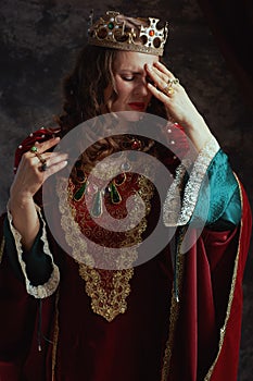 stressed medieval queen in red dress having headache