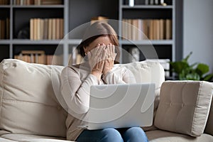 Stressed middle aged woman hiding face with both hands.