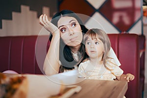 Stressed Mom Sitting with her Child in a Restaurant Booth