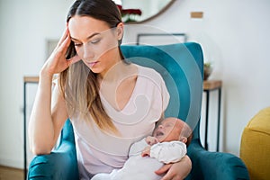Stressed Mother Holding Crying Baby Suffering From Post Natal Depression At Home