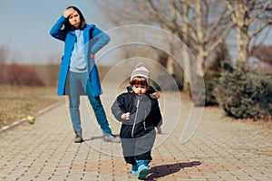 Stressed Mother Supervising Child Playing Outdoors