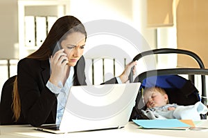 Stressed mother working taking care of her baby at office photo