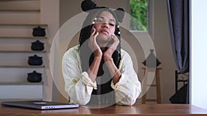 Stressed multitasking young woman has a headache after a hard day at work, feeling tired and overworked, holding her