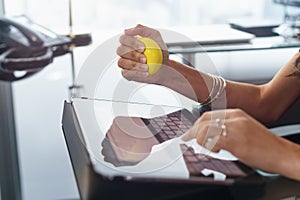 Stressed office worker with anti stress ball types email