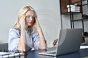 Stressed old business woman suffering from headache after computer work.