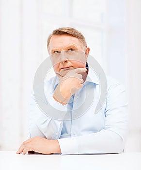 Stressed old man holding head at home