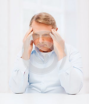 Stressed old man holding head at home