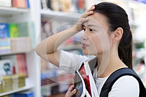 Stressed out female student searching for books in the library