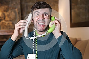 Stressed out man with landline phones cords tangled up