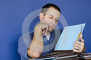 Stressed out man at work reading through files.