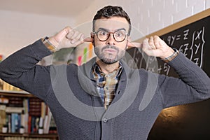 Stressed out teacher blocking ears in classroom