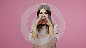 Stressed out, upset brunette woman holding hands around mouth and shouting with loud voice, screaming