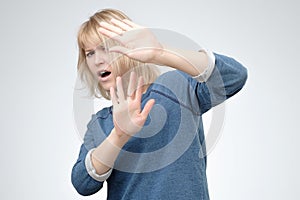 Stressed out woman keeping hands in stop gesture, trying to defend herself as if saying Stop that