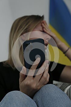 Stressed out woman with Ukrainian flag on the background.