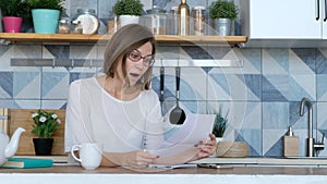 Stressed over bills. Surprized and Unpset woman looking at her financial debts in the kitchen.