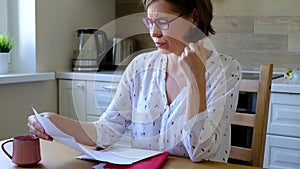 Stressed over bills. Unpset woman looking at her financial debts in the kitchen.