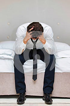 Stressed and overworked businessman sitting on the bed
