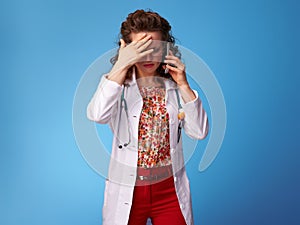 Stressed paediatrician doctor using cell phone on blue