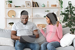 Stressed pregnant woman shouting at husband while he using laptop