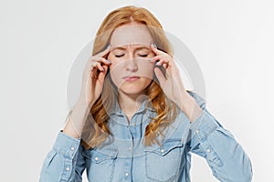 Stressed red hair woman portrait having a migraine headache holding her head in pain and stress isolated over white background