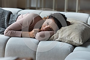 Stressed sad latin woman lying on sofa unable to sleep