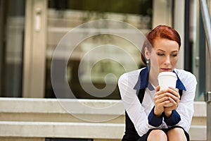 Stressed sad young woman sitting outdoors corporate office