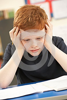 Stressed Schoolboy Studying In Classroom