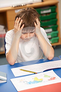 Stressed Schoolboy Studying In Classroom