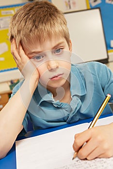 Stressed Schoolboy Studying In Classroom